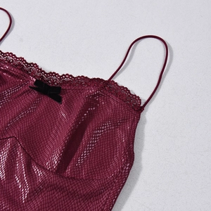 Detail of wine red snakeskin textured fabric with black lace trim and bow accent