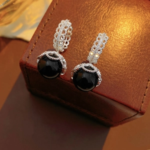 Detailed macro view of vintage gold-plated earrings with black onyx pendants on leather