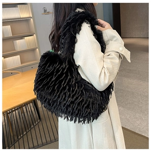 Sac fourre-tout tendance en fausse fourrure noire porté à l'épaule sur manteau beige