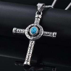Macro detail of silver cross pendant with embossed patterns and blue turquoise stone