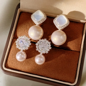 Detail of luxury pearl drop earrings with sparkling zircon flowers and shell accents
