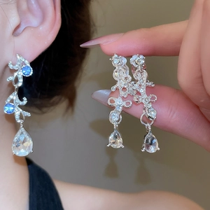 Close-up of sparkling pear-cut blue crystal drop earrings with hollow flower detail