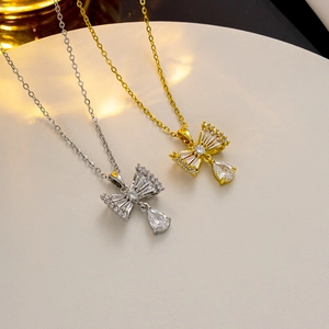 Close-up of bow-knot necklace pendant with a pear-shaped zircon drop on a fine metal chain