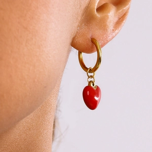 Élégantes créoles dorées avec pendentifs cœur rouge portées par un mannequin chic