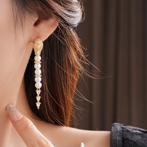 Macro view of elegant snake-shaped drop earrings with white pearls and sparkling crystals