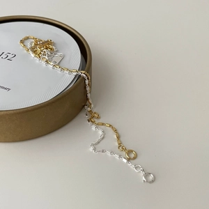 Macro detail of silver and gold square box chain bracelets with circular spring clasps
