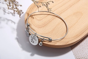 Detail of silver heart charm bracelet with 'Love Mi Mama' engraving on wooden tray