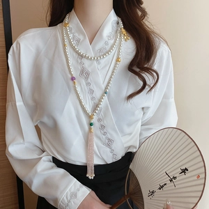 Detail of multi-layer pearl necklace with pink tassel and gold-plated lotus accents