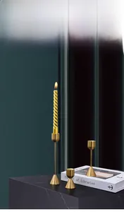Detailansicht goldener Metallkerzenständer in verschiedenen Höhen auf Marmorsockel