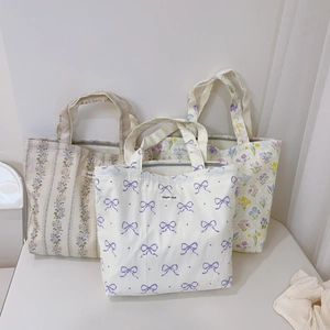 Detailed view of three small canvas tote bags with floral and bow print patterns