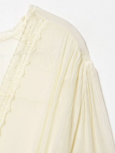 Macro detail of elegant lace trim and pleated texture on a cream-colored mesh shirt