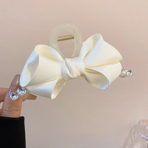 Close-up of off-white satin ribbon bow hair claw with sparkling rhinestones detail