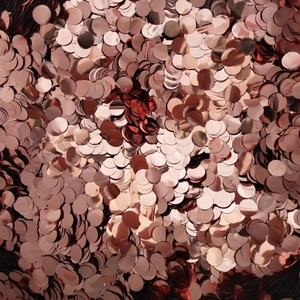 Macro shot of rose gold round confetti sequins with a polished metallic finish