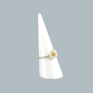 Detailed view of a silver daisy ring with champagne center on a white cone display stand