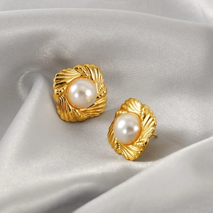 Elegant gold square pearl stud earrings with vintage texture on satin background