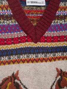 Close-up of Fair Isle jacquard knit vest with horse patterns and brand neck label