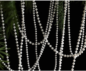 Détail de guirlande en perles blanches décoratives sur des branches de sapin de Noël