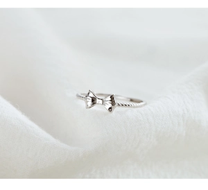 Close-up of a silver bow ring featuring a twisted rope band design on white fabric