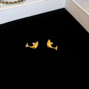 Macro shot of gold whale earrings with sparkling cubic zirconia on black velvet background