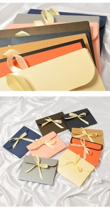Detailed view of colorful envelope-style paper gift bags with decorative silk ribbon bows