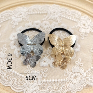 Detailed view of gold and silver alloy butterfly hair ties with dimensions 6.3cm by 5cm