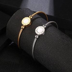 Detailed view of Roman numeral engraved bangles in gold and silver steel finish