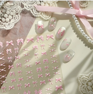 Detailed 3D pink bow nail stickers with white pearls on a lace and ribbon background