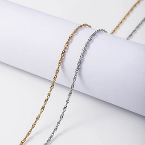 Detail of 18K gold and silver water wave twist necklaces on a clean white display stand