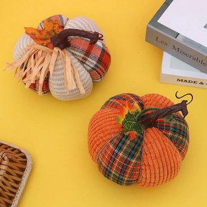 Deko-Kürbisse aus Stoff mit Karomuster und orangefarbenem Cordsamt auf gelbem Hintergrund