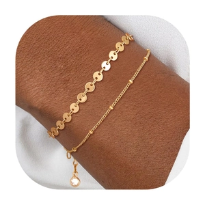 Detail von mehrlagigen vergoldeten Armbändern mit flachen Scheiben und kleinen Perlen