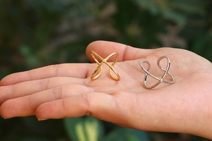 Elegant gold and silver cross rings with zircon stones displayed on fingers outdoors