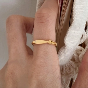 Detail of a golden fish-shaped silver ring on finger with soft lighting and book background