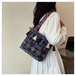 Ethnic woven tote bag detail with colorful patterns, decorative tassels and wide shoulder strap