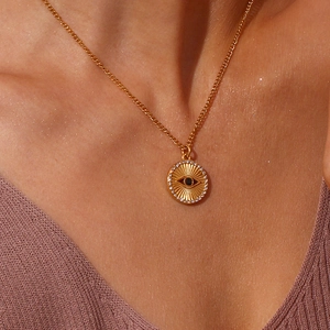 Detailed view of evil eye coin pendant with white zircon inlays on golden chain