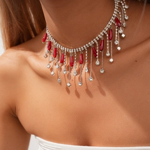 Détail d'un ras du cou argenté avec strass brillants et pendentifs gouttes rouges sur modèle