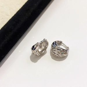 Close-up of silver U-shaped hoop earrings featuring geometric textured metal surfaces