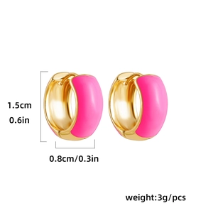 Detail view of gold huggie earrings with pink enamel, showing 1.5cm height and weight