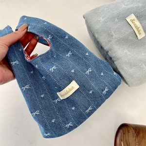 Detail of denim mini tote bag featuring bow patterns and branded woven label