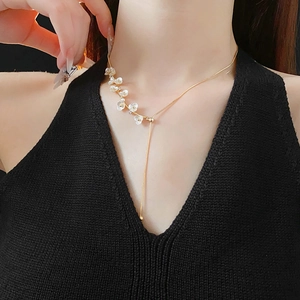Detailed view of flower pearl necklace with gold tassel chain on a model neckline