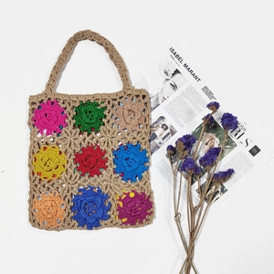 Flat lay of handmade crochet tote bag with colorful floral patchwork squares and flat handle