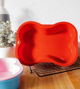 Macro shot of large red bone-shaped silicone baking mold on a professional cooling rack
