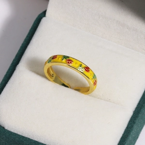 Detailed macro view of yellow gold open ring with colorful enamel flower in a velvet box