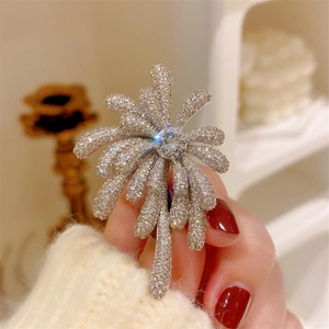 Detailed close-up of a sparkling silver brooch with zircon fireworks design on a hand