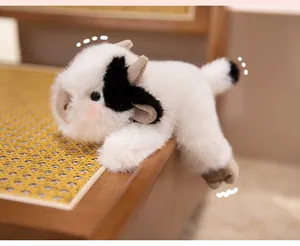Close-up of soft black and white cow plush toy lying on a woven chair with cute details