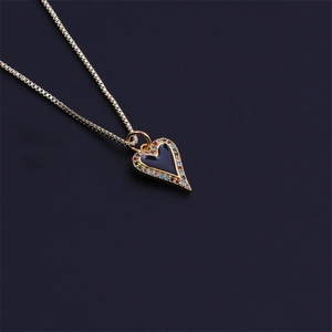 Golden heart necklace with black inlay and colorful zircon border on dark background