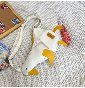 Detailed view of white canvas duck crossbody bag with yellow feet on a textured knit mat