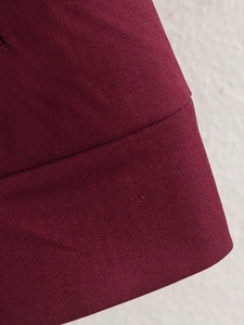 Close-up of burgundy twill fabric showing detailed weaving texture and premium stitching