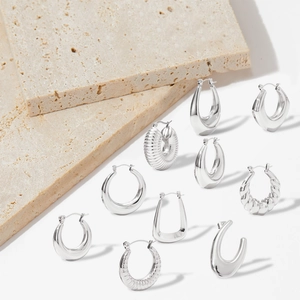 Flat lay of diverse silver hollow earrings with smooth and textured finishes on stone