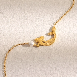 Vue détaillée du pendentif sirène avec perle blanche sur bracelet en acier doré 18K