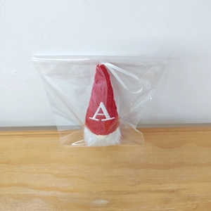 Detail of red knit Christmas gnome ornament with white embroidered letter A on hat